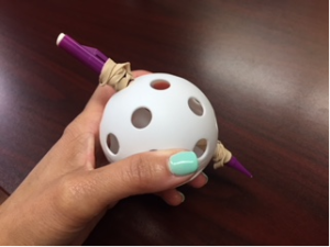 This is a picture of the wiffle ball and pencil with elastics at either end of the pencil towards the wiffle ball holes