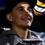 A young man in a Boston Bruins hat looking upwards and to their left.