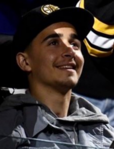 A young man in a Boston Bruins hat looking upwards and to their left.